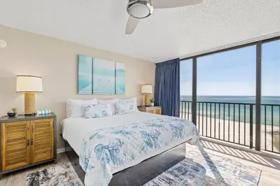 a bedroom with a bed with a view of the ocean at Sandpiper Beacon Beach Resort in Panama City Beach