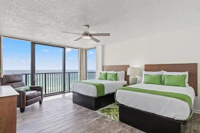 a bedroom with two beds and a balcony at Sandpiper Beacon Beach Resort in Panama City Beach