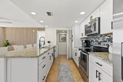 a kitchen with white cabinets and granite counter tops at Sandpiper Beacon Beach Resort in Panama City Beach