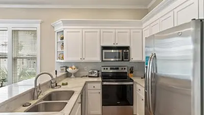 a kitchen with white cabinets and a stainless steel refrigerator at Take It Eeaasy in Panama City Beach