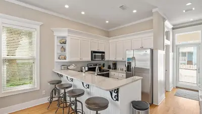 a kitchen with white cabinets and bar stools at Take It Eeaasy in Panama City Beach