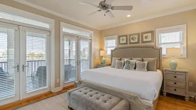 a bedroom with a bed and a balcony with windows at Take It Eeaasy in Panama City Beach