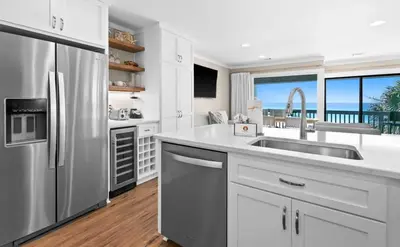 a kitchen with white cabinets and a stainless steel refrigerator at Latitude 29 Unit 22 in Panama City Beach