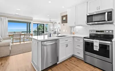 a kitchen with white cabinets and a view of the ocean at Latitude 29 Unit 22 in Panama City Beach