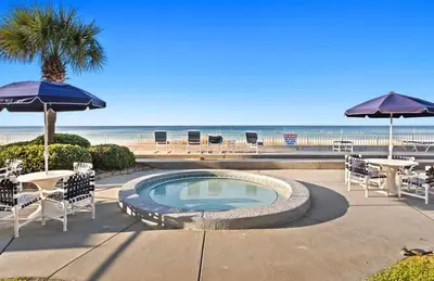 a swimming pool with tables and umbrellas next to the beach at Latitude 29 Unit 22 in Panama City Beach