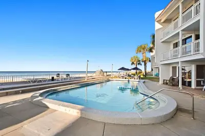 a swimming pool next to a building and the beach at Latitude 29 Unit 22 in Panama City Beach