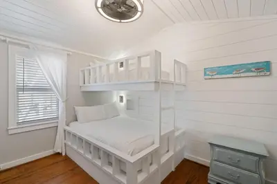 a white bedroom with a bunk bed and a window at Tutti Frutti in Santa Rosa Beach