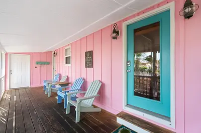 a row of chairs on a porch with a pink wall at Tutti Frutti in Santa Rosa Beach