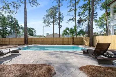 a swimming pool with two chairs and a fence at Tutti Frutti in Santa Rosa Beach