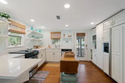 a kitchen with white cabinets and a wooden floor at Tutti Frutti in Santa Rosa Beach