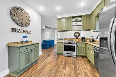 a kitchen with green cabinets and a large clock on the wall at The Grey Gull in Inlet Beach