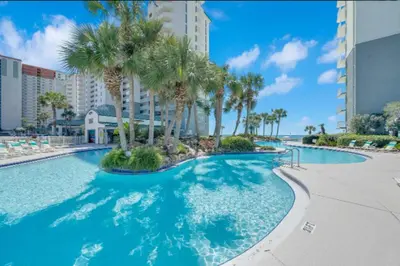 a large swimming pool with palm trees in a resort at Mermaid's Delight - PCB, FL in Panama City Beach