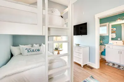 a bedroom with a white bunk bed and a tv at Margaritas and Parrots in PCB Beachy Bungalow! in Panama City Beach