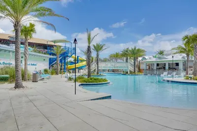 a swimming pool with palm trees and a slide at Margaritas and Parrots in PCB Beachy Bungalow! in Panama City Beach