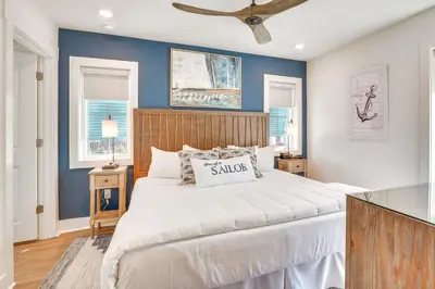 a bedroom with a large white bed and blue walls at Margaritas and Parrots in PCB Beachy Bungalow! in Panama City Beach