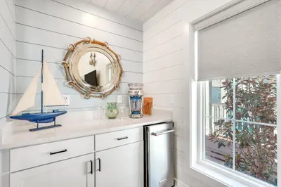 a bathroom with a mirror and a sailboat on a counter at Margaritas and Parrots in PCB Beachy Bungalow! in Panama City Beach