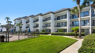 a large white building with palm trees and grass at Emerald Hill 35 in Santa Rosa Beach