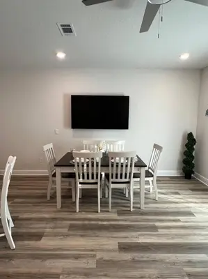 a dining room with a table and chairs and a flat screen tv at PCB Townhome in Panama City Beach