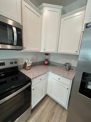 a kitchen with white cabinets and a stove and microwave at PCB Townhome in Panama City Beach