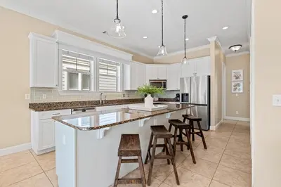a kitchen with white cabinets and bar stools at Seeking Sunsets 30A in Rosemary Beach