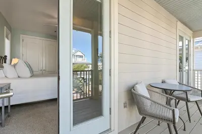 a porch with a table and a bed and a balcony at Seeking Sunsets 30A in Rosemary Beach