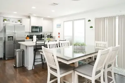 a kitchen with a glass table and white chairs at Boat Dock! Canal-Front Family Retreat in PCB in Panama City Beach
