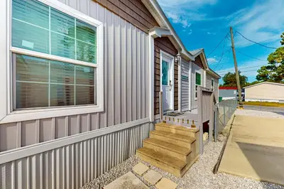 a home with a fence and stairs next to a building at Boat Dock! Canal-Front Family Retreat in PCB in Panama City Beach