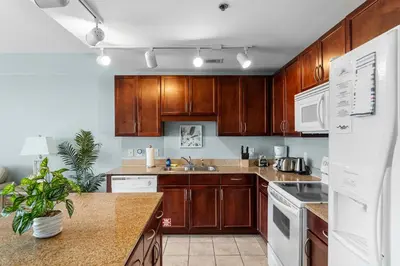 a kitchen with wooden cabinets and a white refrigerator at Oceanview Family Friendly Resort Low Floor Condo! Steps 2 Beach! by Dolce Vita Getaways PCB in Panama City Beach