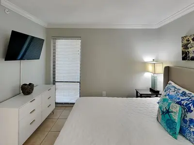 a white bedroom with a bed and a television at Edgewater Tower III #708 in Panama City Beach