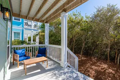 a porch with blue chairs and a wooden bench at 30A Lemon Shello in Seacrest