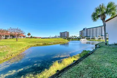 a river with a palm tree and buildings in the background at Edgewater Golf Villa 3101 in Panama City Beach