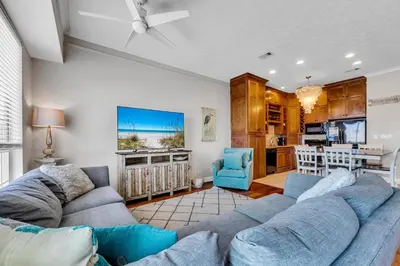a living room with a blue couch and a kitchen at The Palms A3 in Panama City Beach