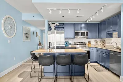 a kitchen with blue cabinets and a island with bar stools at Laketown Wharf #1407 in Panama City Beach