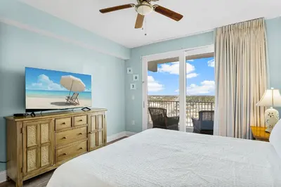 a bedroom with a bed and a television and a balcony at Laketown Wharf #1931 in Panama City Beach