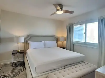 a bedroom with a white bed with a ceiling fan at Emerald Beach #1032 in Panama City Beach