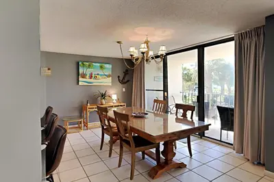 a dining room with a table and chairs and a room with a balcony at Edgewater Tower I #111 in Panama City Beach