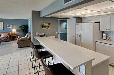 a kitchen with a counter and chairs and a refrigerator at Edgewater Tower I #111 in Panama City Beach