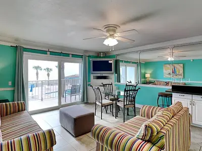 a living room with green walls and a table and chairs at Summit Beach Resort #222 in Panama City Beach