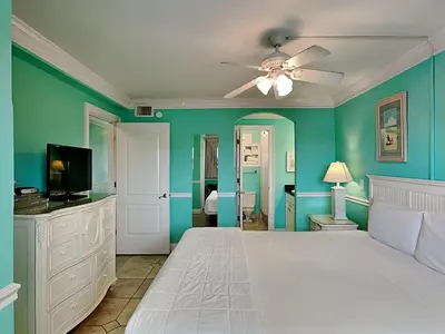 a bedroom with green walls and a bed with a ceiling fan at Summit Beach Resort #222 in Panama City Beach