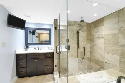 a bathroom with a glass shower and a sink at Edgewater Leeward #307 in Panama City Beach