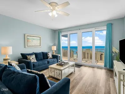 a living room with a couch and a television with a view of the ocean at Laketown Wharf 1523 by Emerald Coast Retreats in Panama City Beach