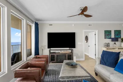 a living room with a television and a couch and chairs at Treasure Island #1401 in Panama City Beach
