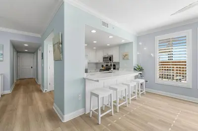 a kitchen with a counter and stools in a room at Treasure Island #0101 in Panama City Beach