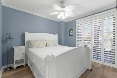 a bedroom with a white bed and a ceiling fan at Treasure Island #0101 in Panama City Beach