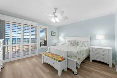 a white bedroom with a bed and a window at Treasure Island #0101 in Panama City Beach
