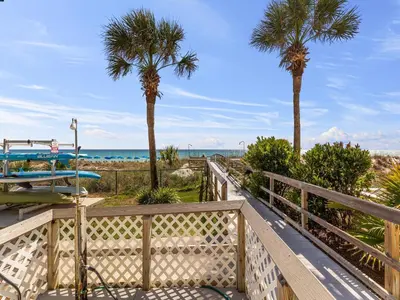 a walkway to the beach with palm trees and a surfboard at Moonspinner 415A in Panama City Beach