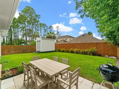 a backyard with a table and chairs and a grill at The Pinetree Retreat in Panama City Beach