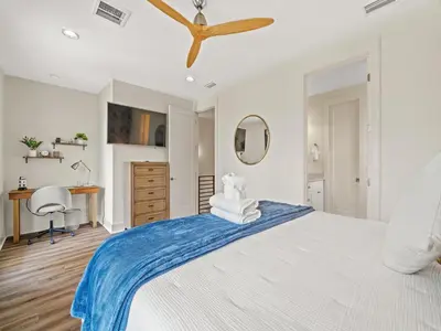 a bedroom with a large white bed with a ceiling fan at The Pinetree Retreat in Panama City Beach