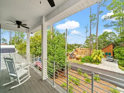 a porch with a rocking chair and a view of a house at The Pinetree Retreat in Panama City Beach