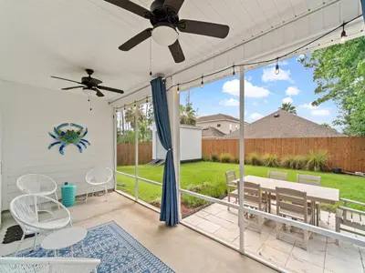 a screened in porch with a ceiling fan and chairs at The Pinetree Retreat in Panama City Beach